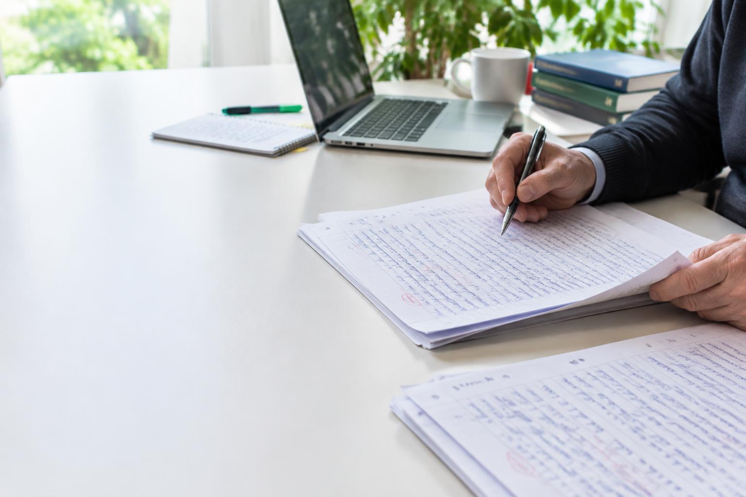 Revisión de exámenes manuscritos en una mesa de trabajo